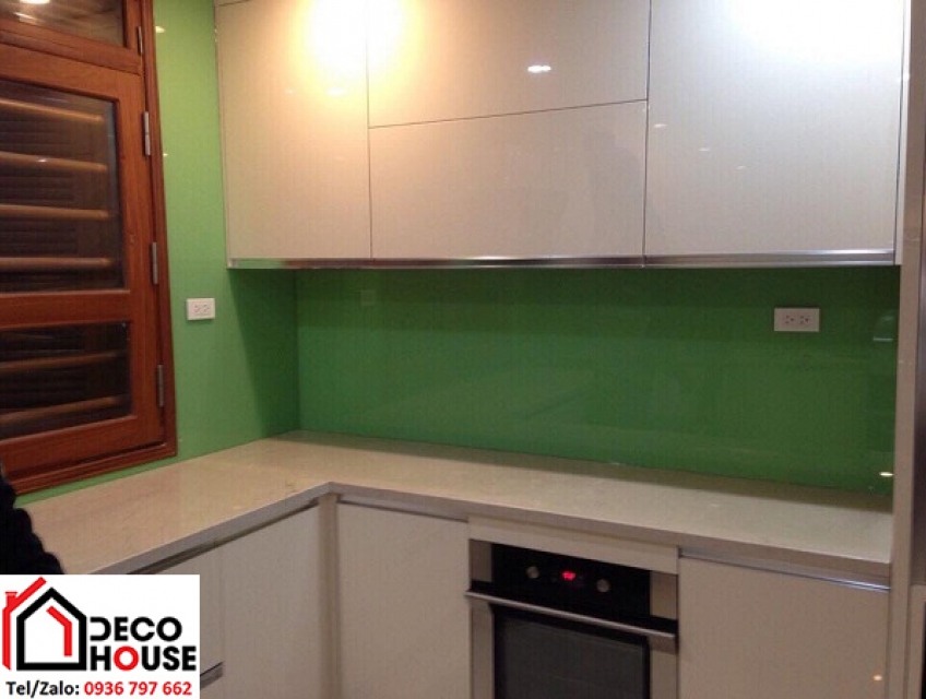 Sự kết hợp giữa kính ốp bếp màu xanh cốm và ánh sáng đèn bếp